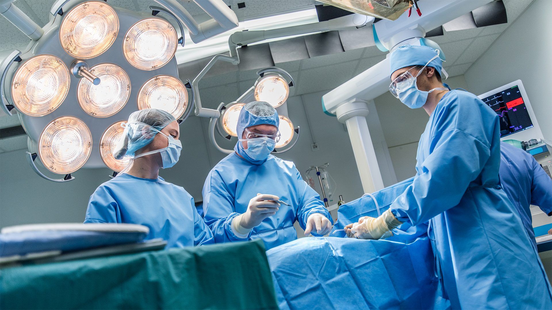 three surgeons in theatre operating on a patient