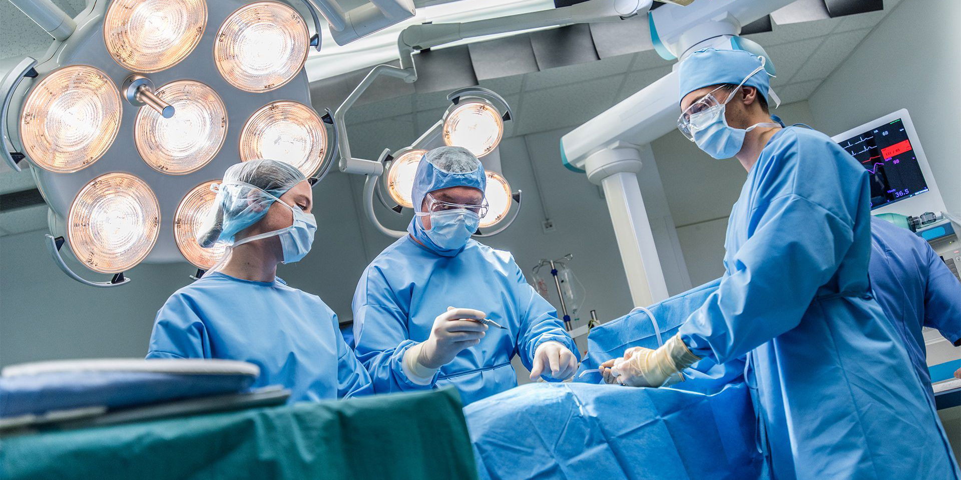 three surgeons in theatre operating on a patient