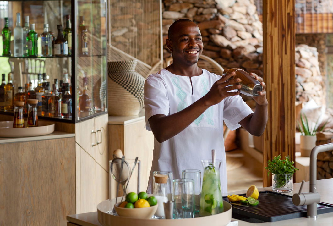 barman preparing drinks on deck at Singita Faru Faru lodge Serengeti