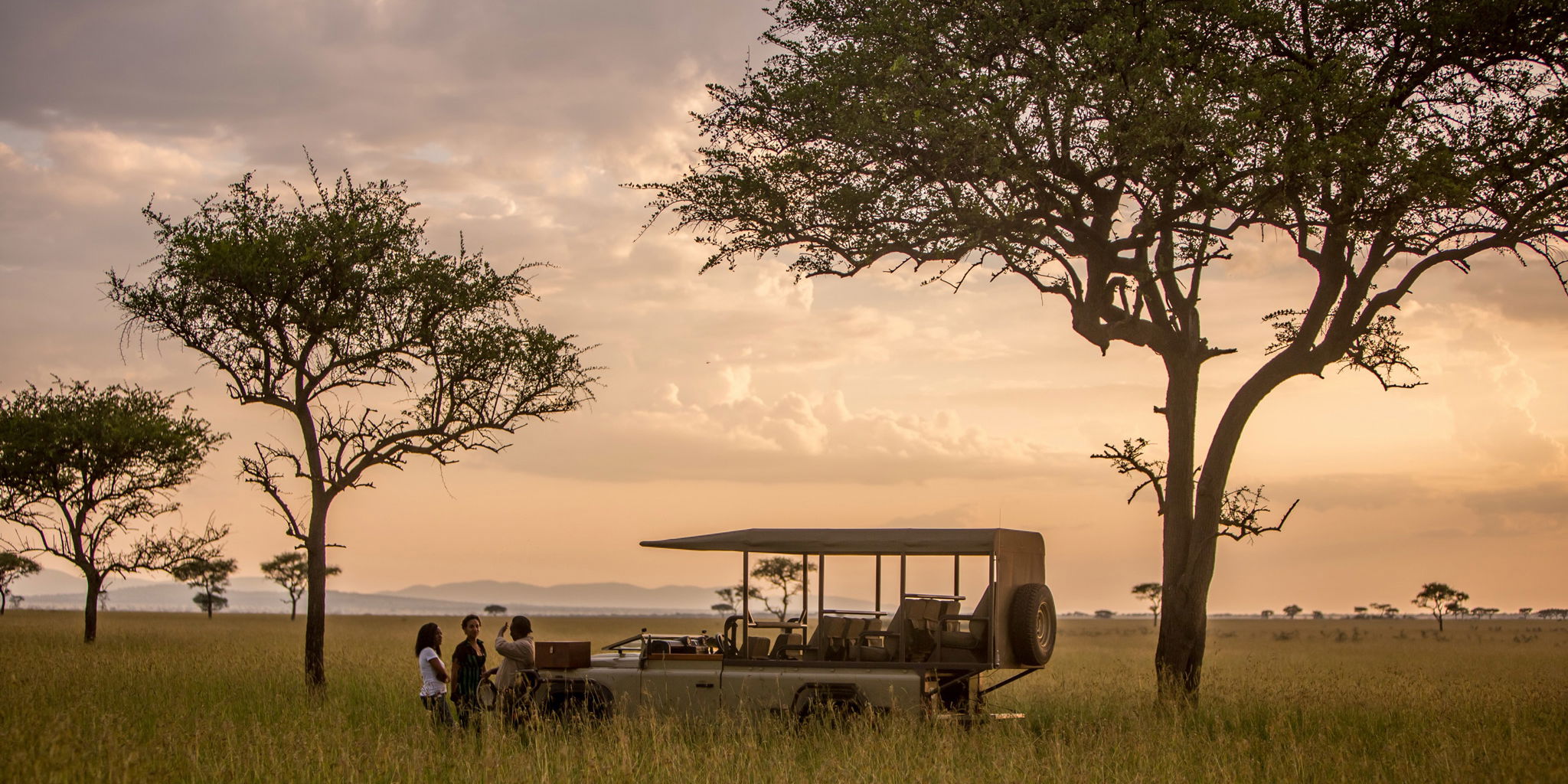 game drive vehicle at sunset in Serengeti with sundowners at Singita Faru Faru lodge Serengeti