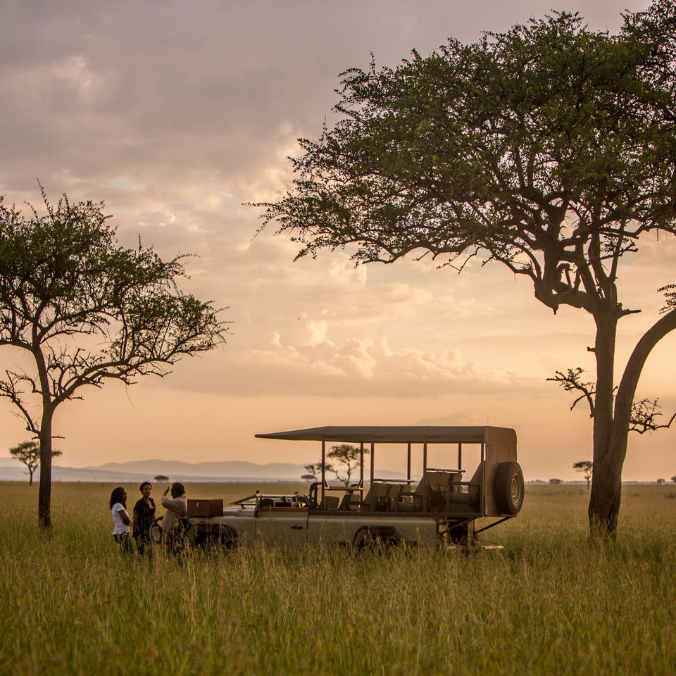 game drive vehicle at sunset in Serengeti with sundowners at Singita Faru Faru lodge Serengeti