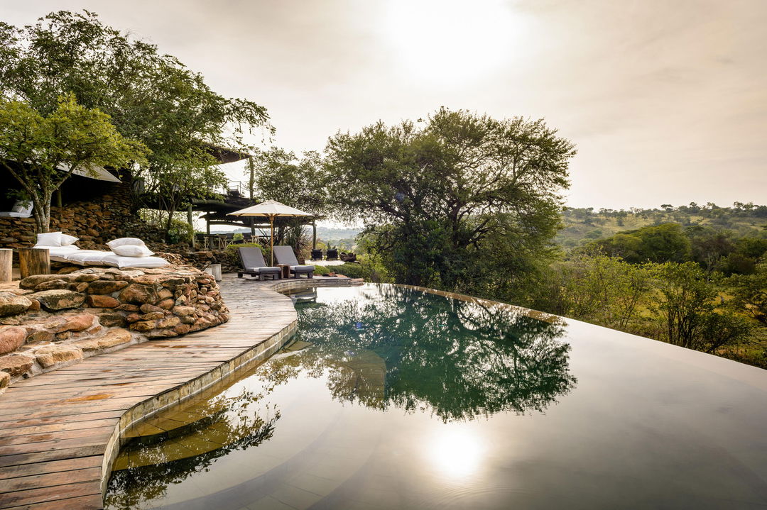 sunset view of the lap pool and loungers at Singita Faru Faru lodge Serengeti