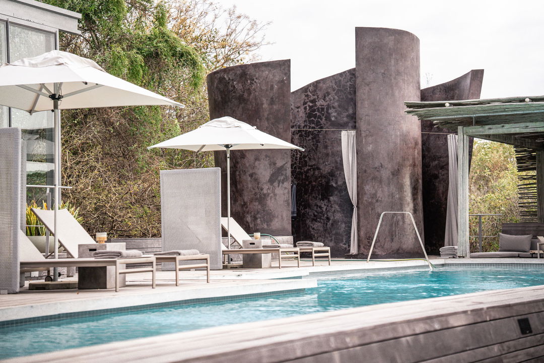swimming pool with umbrellas and chairs at singita lebombo main lodge
