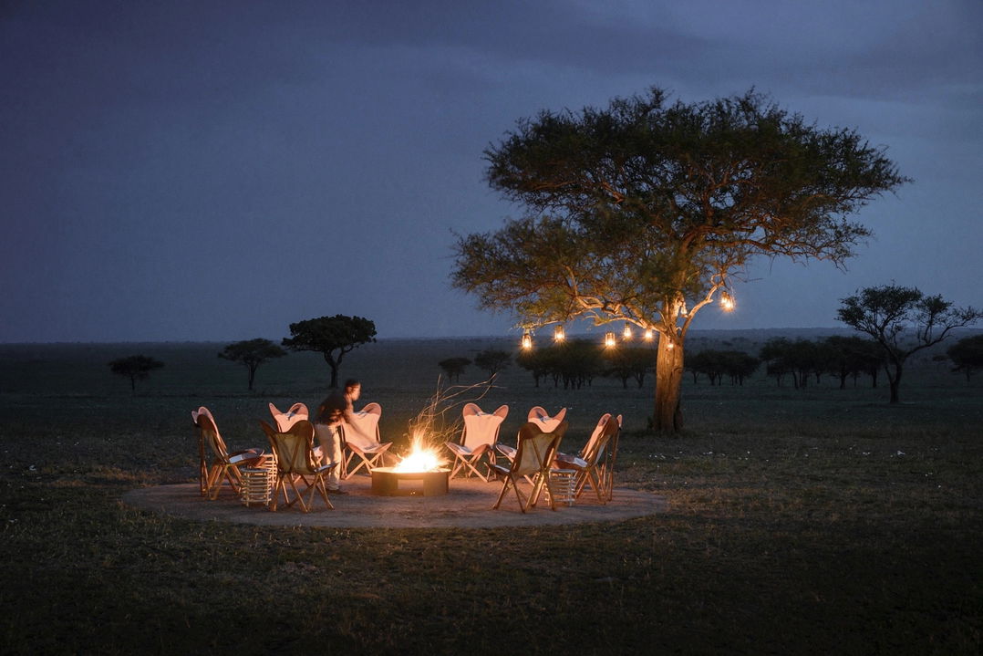 bush dinner setting under tree by tables set on the deck of Singita Sabora Tented Camp Serengeti 