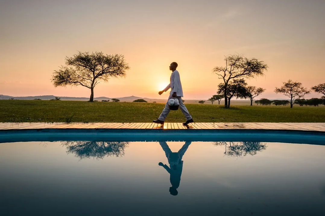 staff prepping pool in morning sun by Singita Sabora Tented Camp Serengeti 
