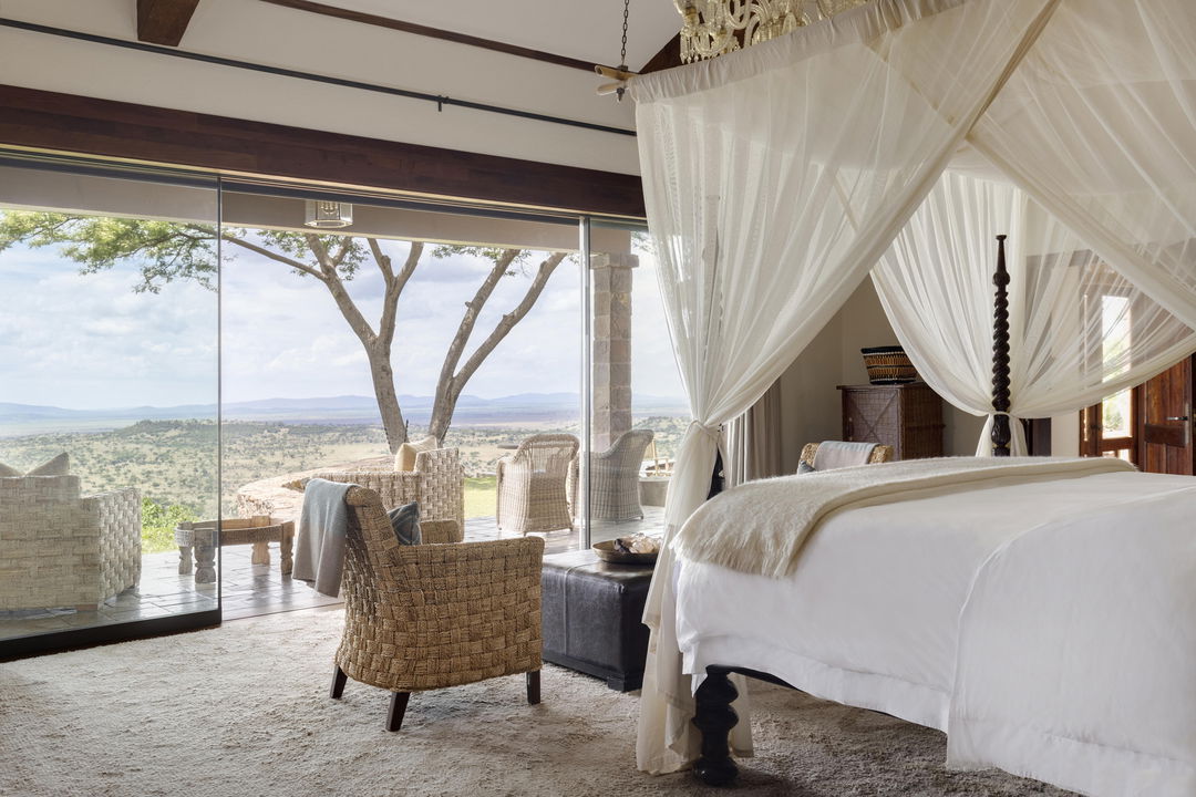 bedroom with open balcony and views at Singita Sasakwa lodge in Serengeti