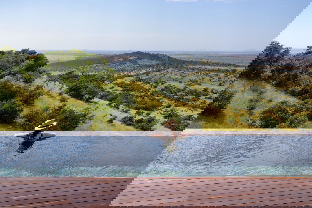 lady guest in the main rim pool of Singita Sasakwa lodge overlooking the Serengeti