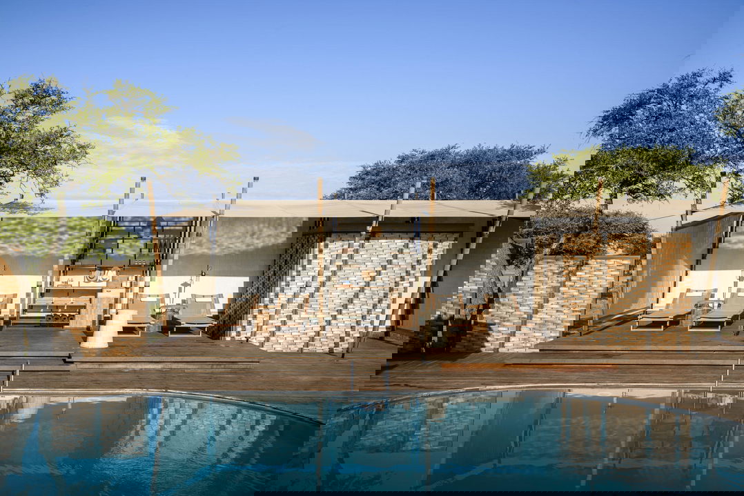 main pool facilities with loungers and sala at lady guest in the main rim pool of Singita Sasakwa lodge overlooking the Serengeti