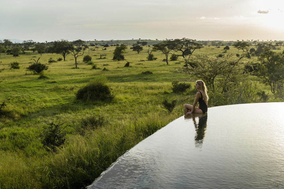 lady guest in the main pool of Singita Sasakwa lodge overlooking the Serengeti