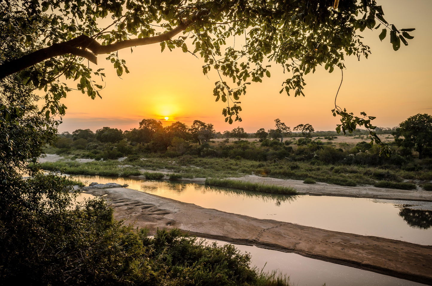 Sunset on river with lush bush in background at Singita boulders safari  lodge