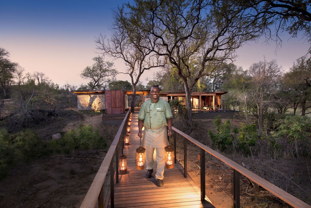 staff carrying lanterns on bridge at &Beyond Tengile River Lodge Sabi Sands
