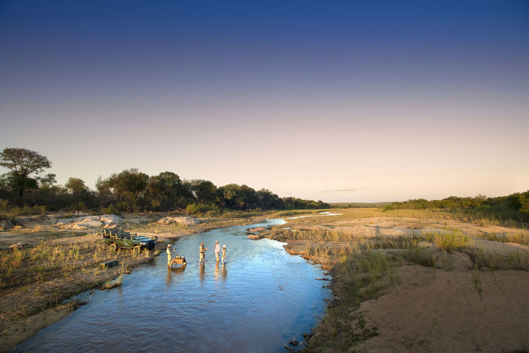 guests in river with sundowners at &Beyond Tengile River Lodge Sabi Sands
