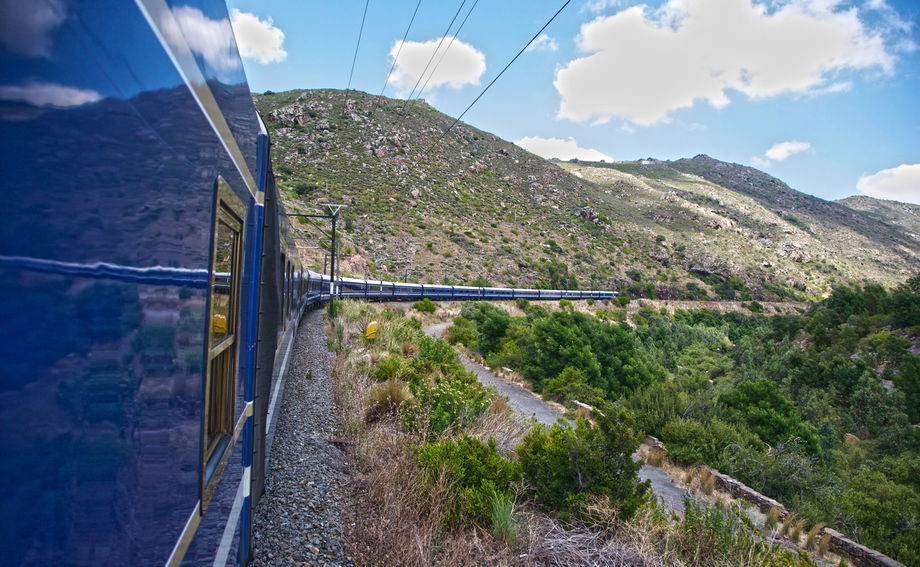 outside view of blue train snaking through countryside of south Africa
