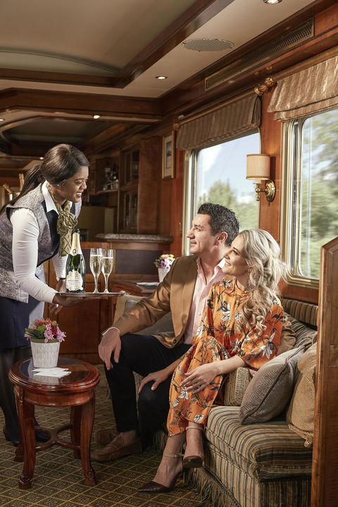 couple served champagne in the lounge cart of the Blue Train