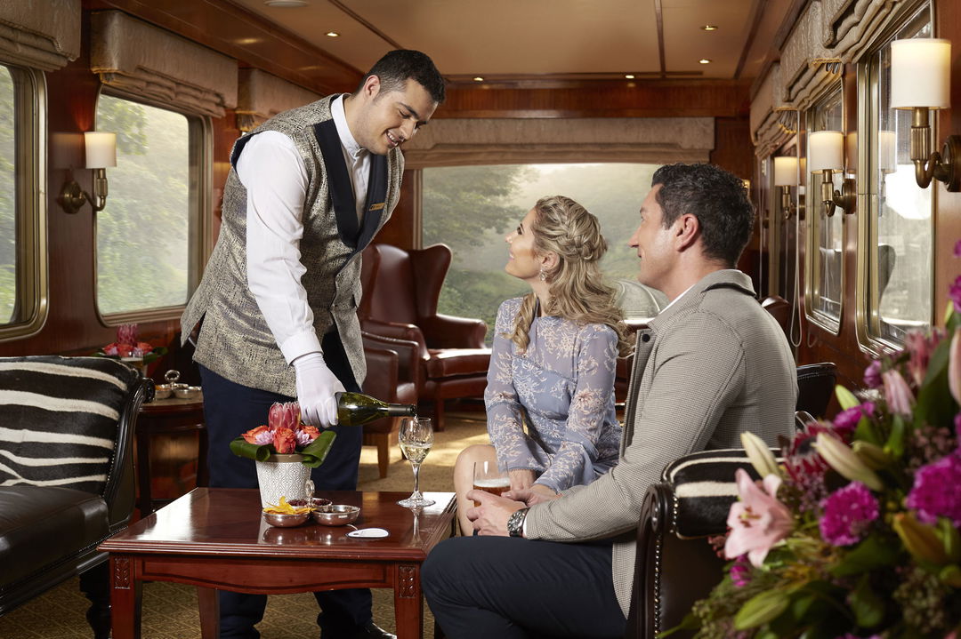 guests served red wine in observation cart of Blue Train