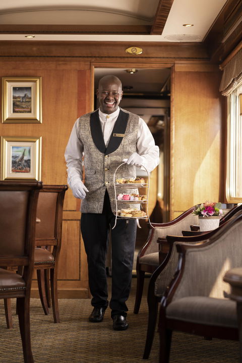 waiter carrying pastries and snacks in a silver tray on Blue Train South Africa