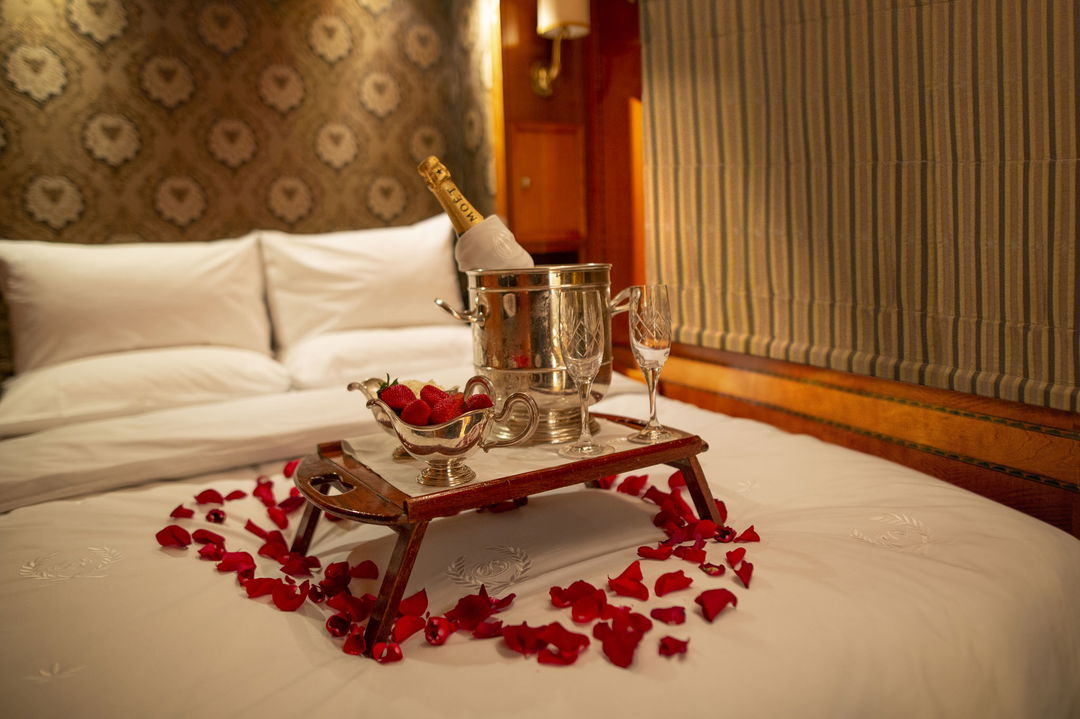 rose petals on bed with champagne bucket in a suite of the Blue Train