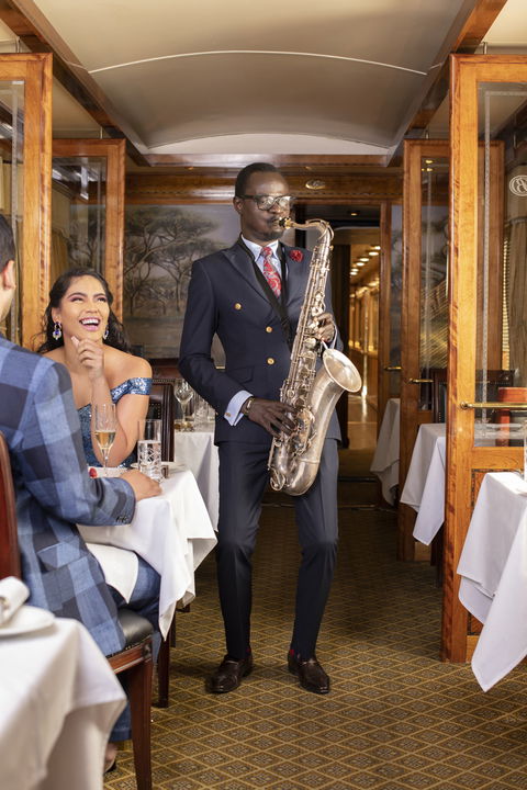 entertainer playing saxophone to guests on the Blue Train