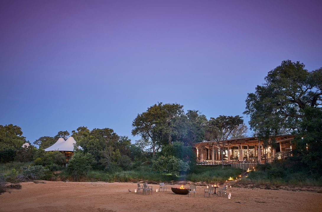 river view of fireplace in front of Thornybush Saseka tented camp at sunset