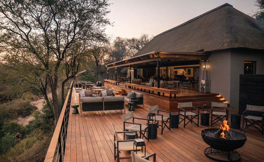 fireplace and dining area on deck of thornybush simbambili lodge at sunset