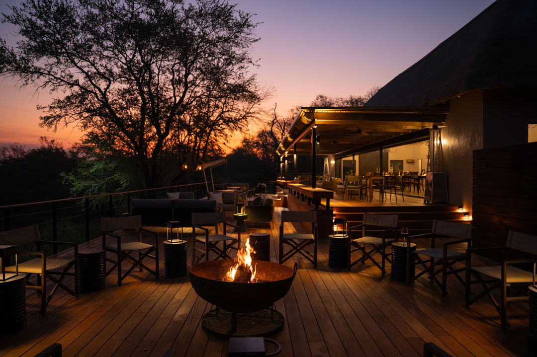 fire pit and dining area on main deck of thornybush simbambili lodge at sunset