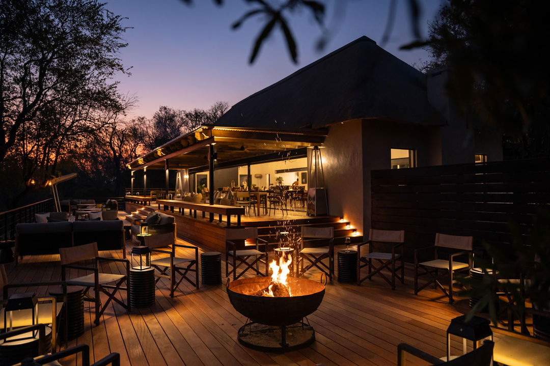 fireplace and chairs on deck at night by Simbambili lodge Thornybush