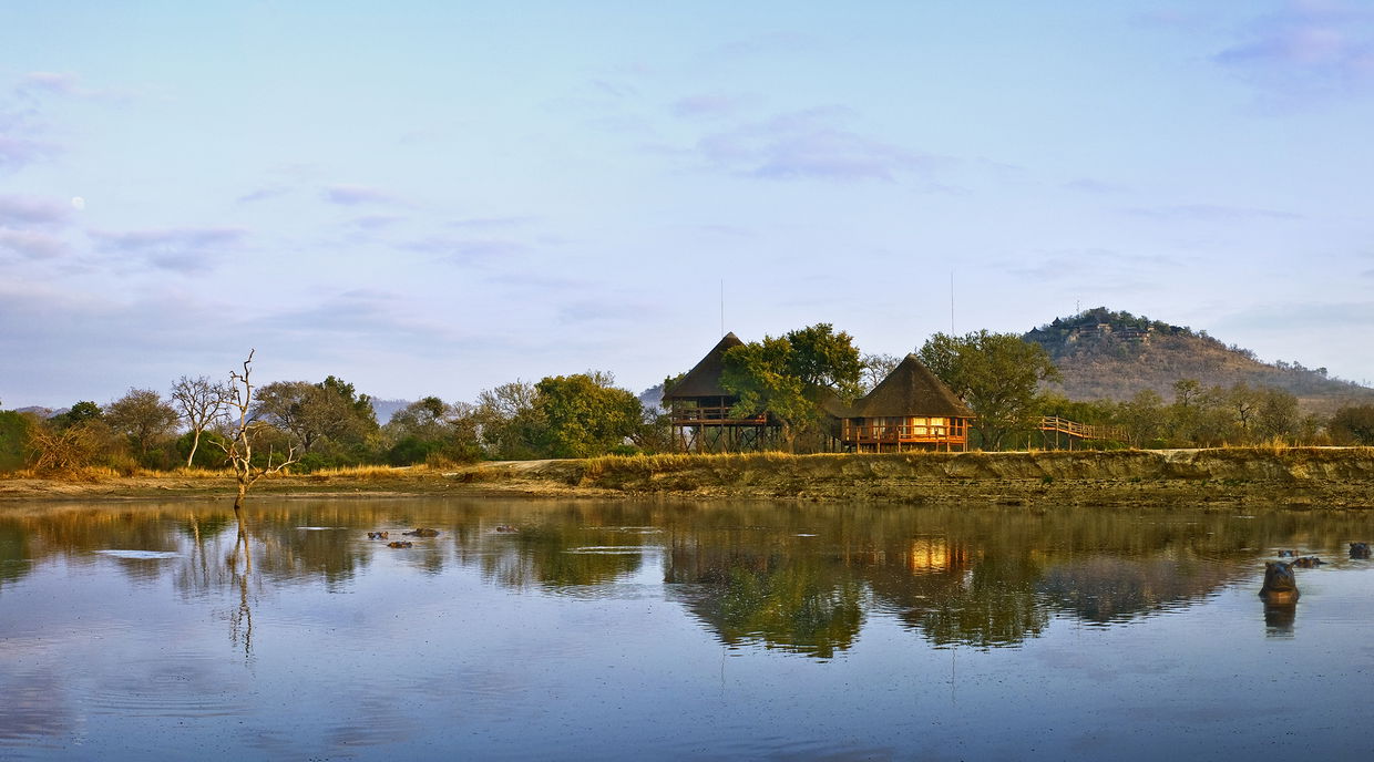 full view of ulusaba safari lodge behinf big watering hole at sunset