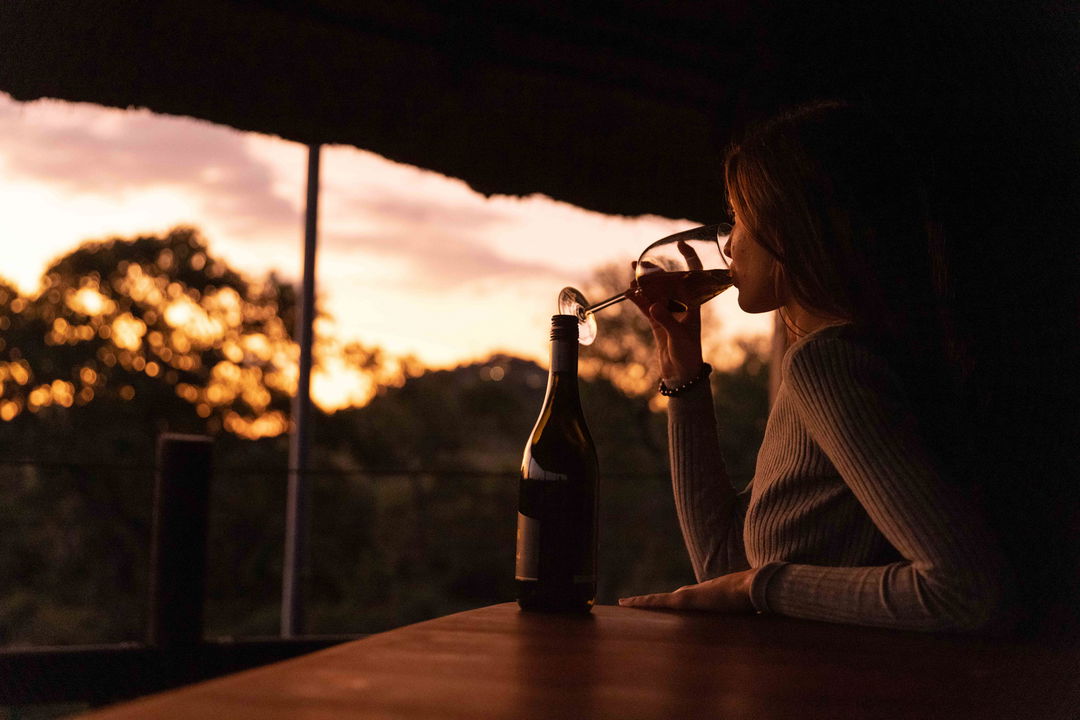 lady guest enjoying red wine on deck at ulusaba safari lodge at sunset