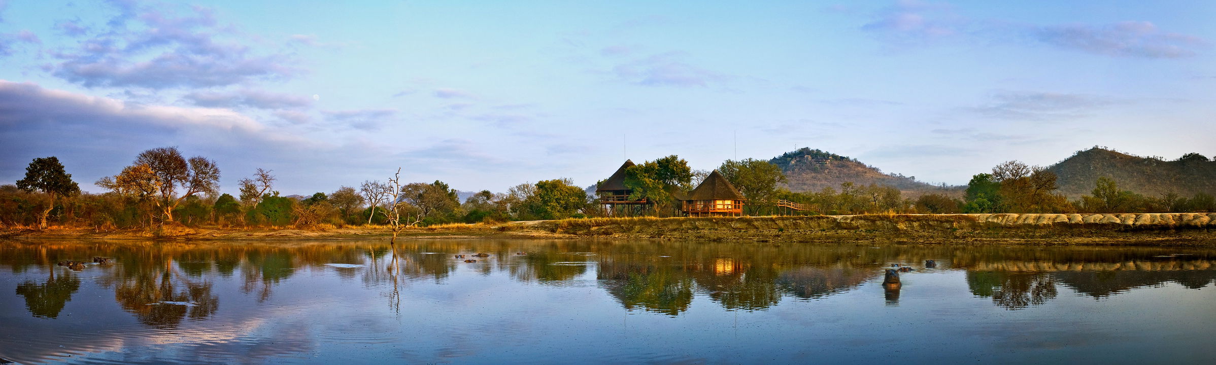 full view of ulusaba safari lodge behind big watering hole at sunset