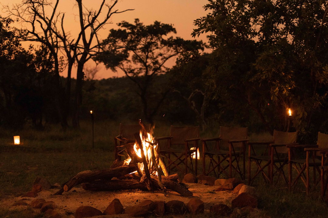 fireplace boma with African sunset in backdrop by Ulusaba safari lodge