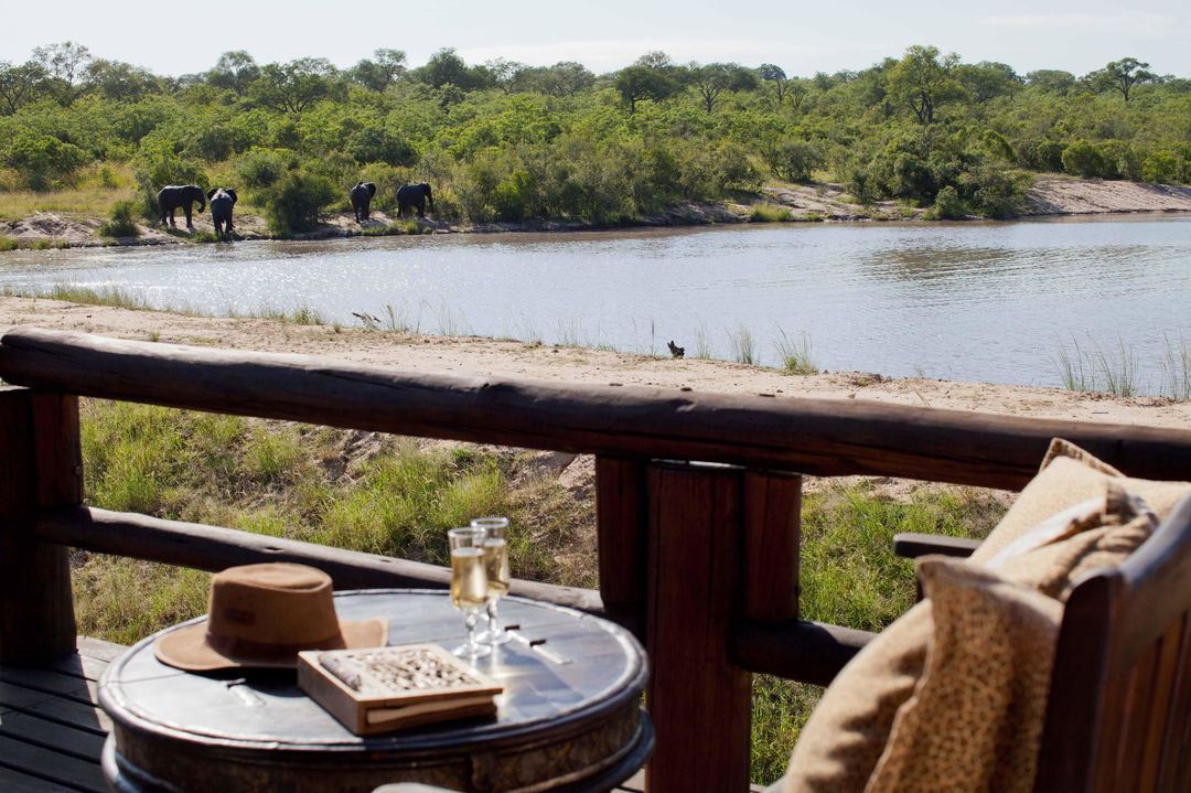 Table on deck with book, drinks and safari hat overlooking the dam at Ulusaba safari lodge