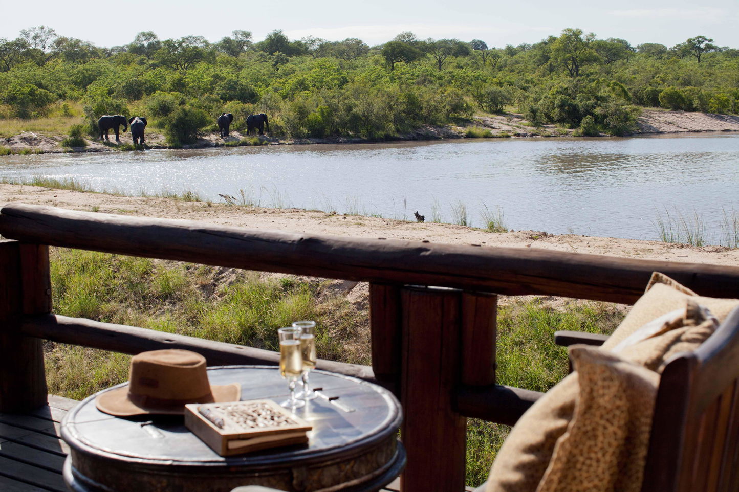 Table on deck with book, drinks and safari hat overlooking the dam at Ulusaba safari lodge