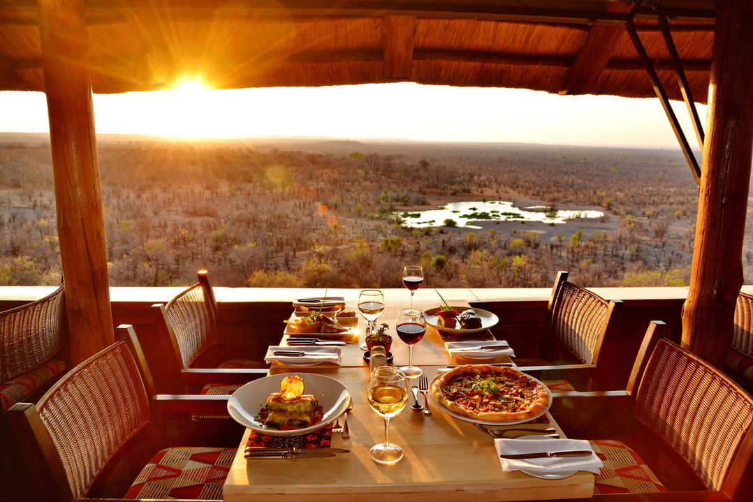 table set for sunset supper at Victoria falls safari lodge Zimbabwe with view of waterhole in valley below