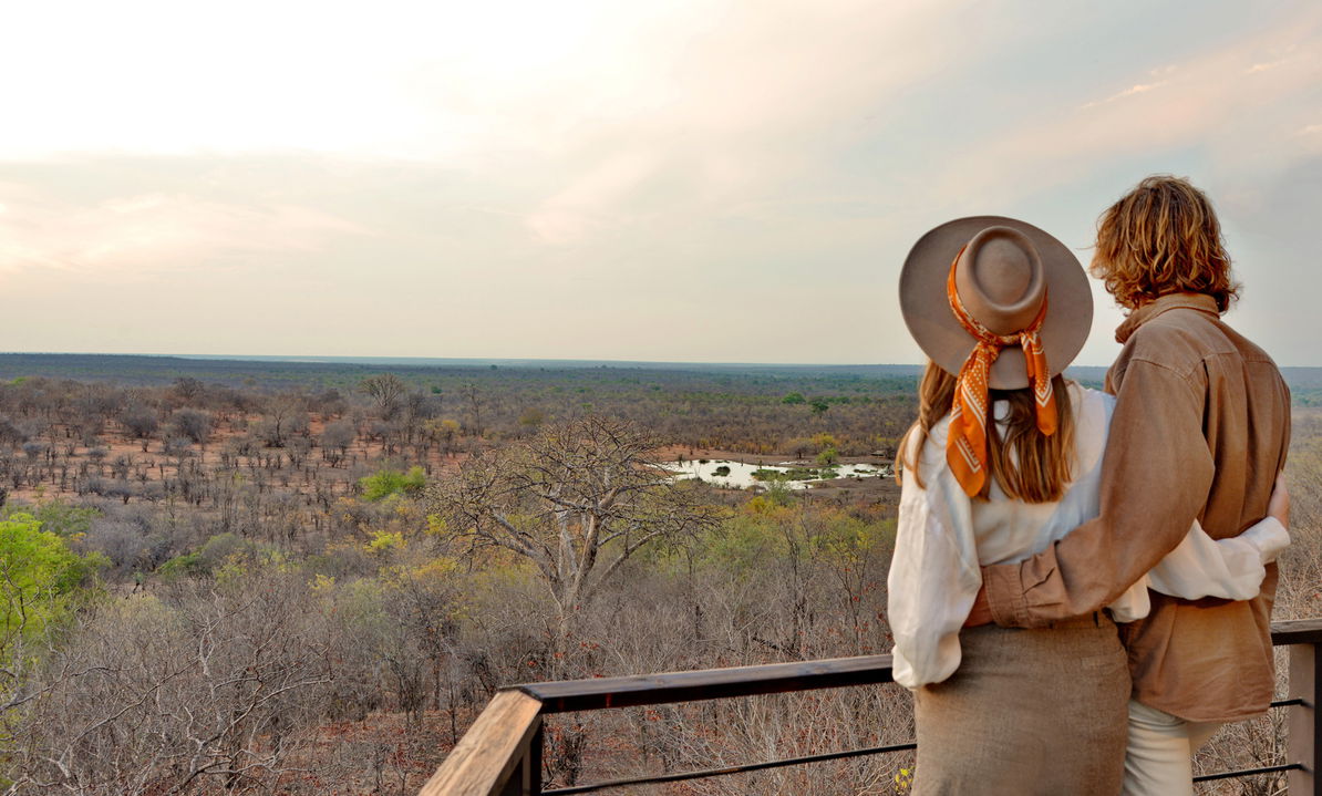 couple viewing the waterhole with elephants from the deck of Victoria falls safari lodge