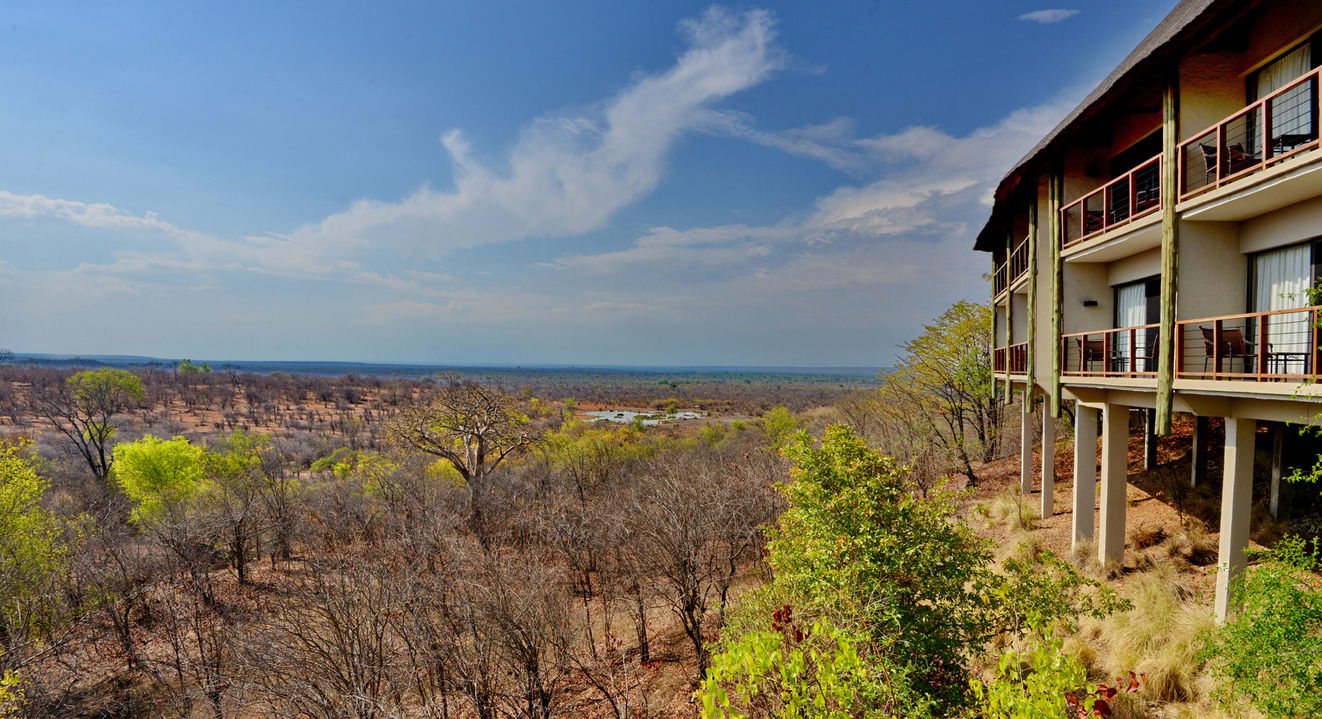 side view of lodge exterior and water hole with elephants at Victoria falls safari lodge Zimbabwe 