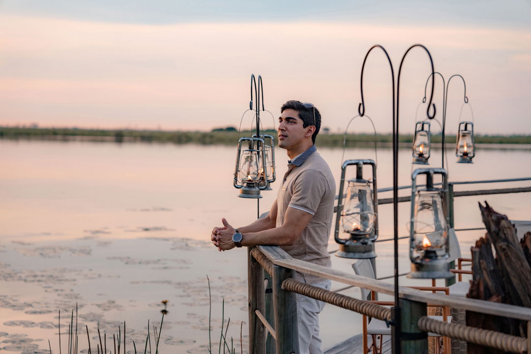guest on the viewing deck of wilderness duma tau camp botswana at sunset