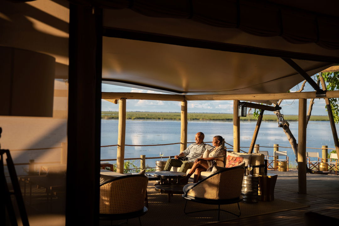 guests having sundowners on deck of main camp by wilderness duma tau camp botswana