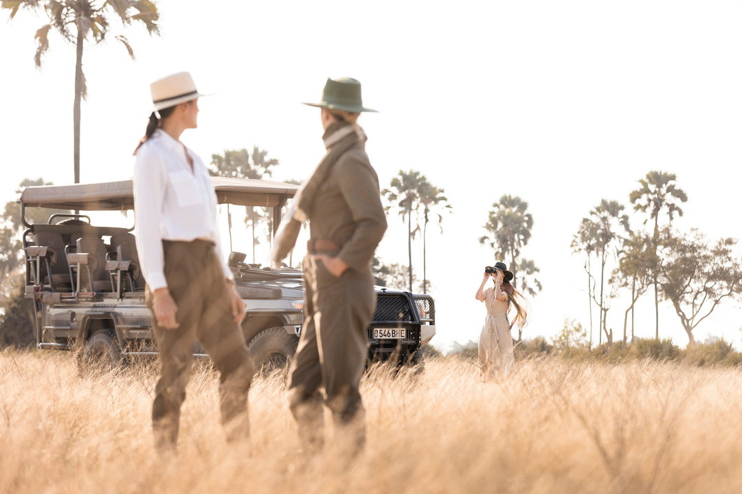 two ladies on plains of Okavango delta in front of game drive vehicle of Little mombo camp