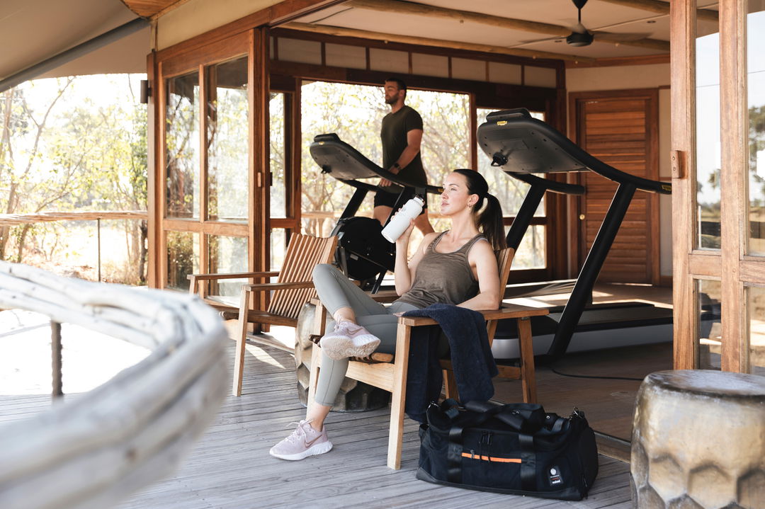 lady guest in front of gym drinking water by little mombo Wilderness