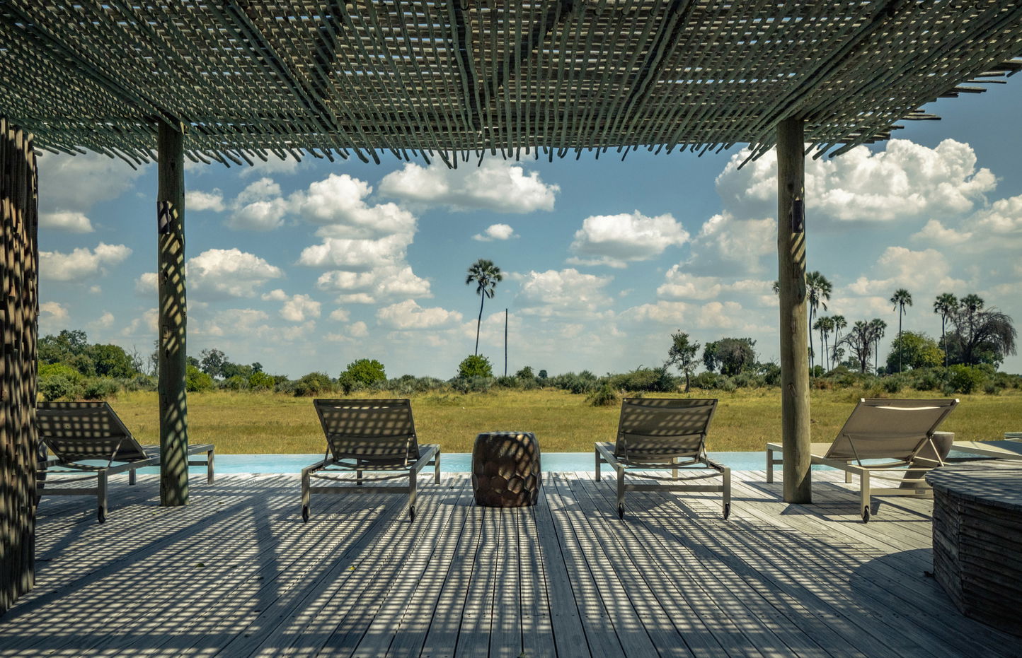 pool deck with loungers and a view of delta at Okavango Delta by Little Mombo Wilderness