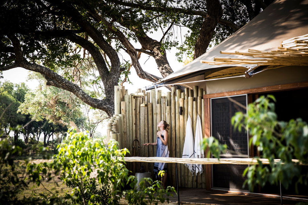 guest in outdoor shower of suite by Little mombo camp Wilderness