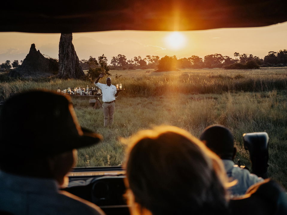 guide welcoming guests with drinks returning from safari by Little Mombo Wilderness