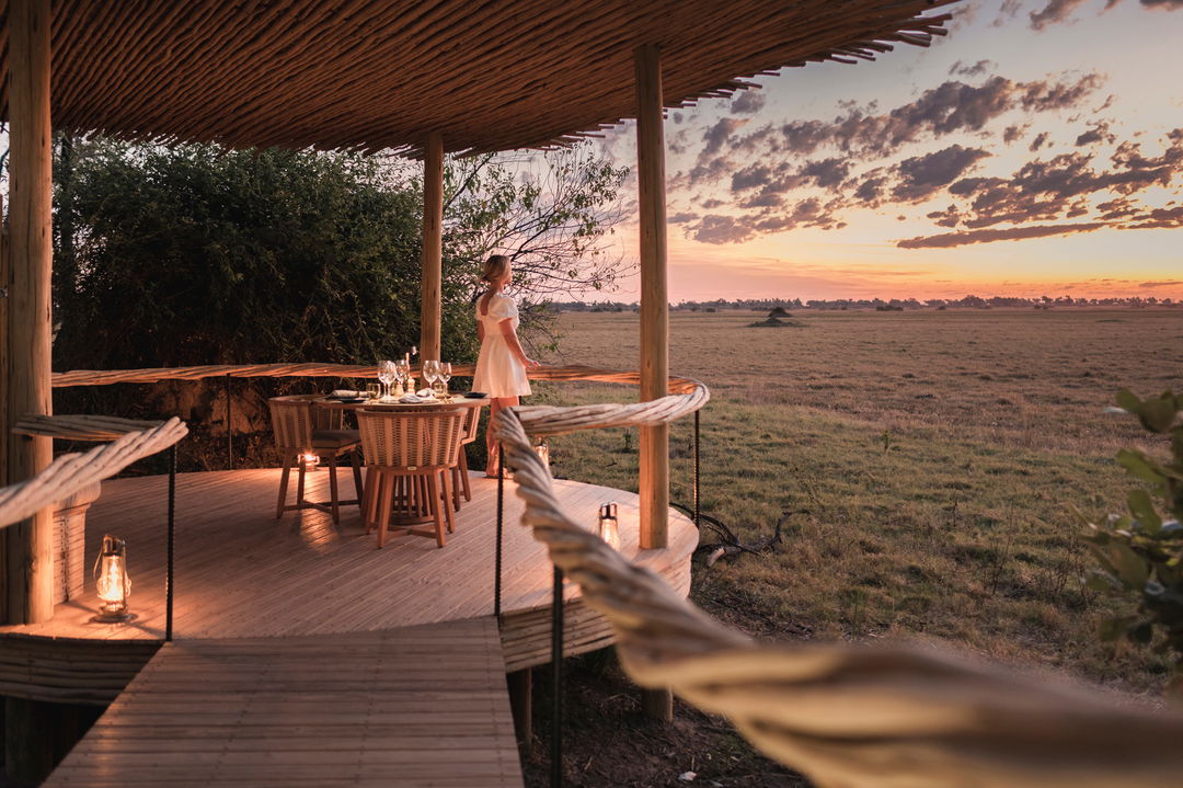 lady on deck by table set for dinner with view of delta at Wilderness Mombo Camp