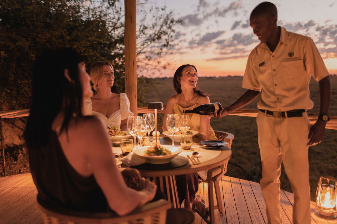 lady guests having supper and wine at Wilderness Mombo Camp in the Okavango Delta