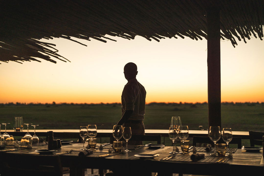 waiter getting tables ready for supper at Wilderness Mombo Camp in the Okavango Delta