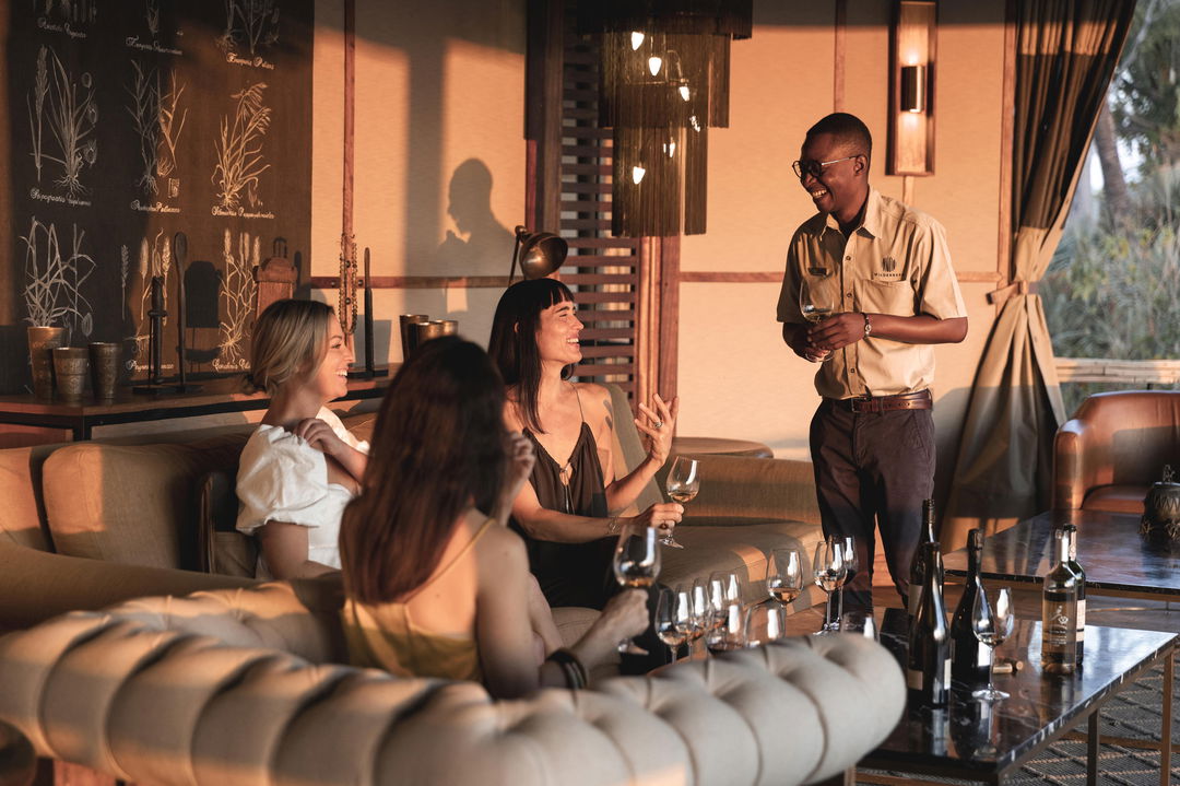 sommelier serving wine to ladies on deck at Wilderness Mombo Camp in the Okavango Delta