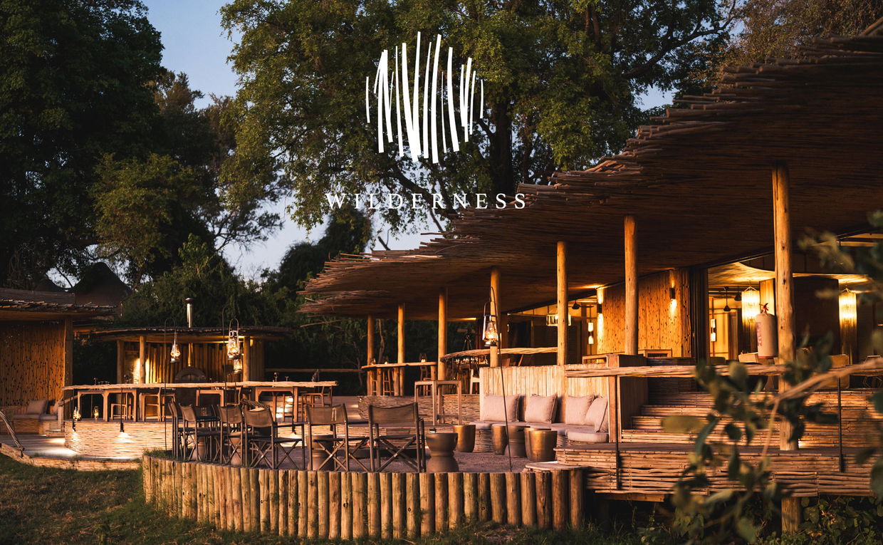 view from below of viewing deck at sunrise on the Okavango delta at Wilderness Mombo Camp with wilderness logo overlay view from below of viewing deck at sunrise on the Okavango delta at Wilderness Mombo Camp with wilderness logo overlay