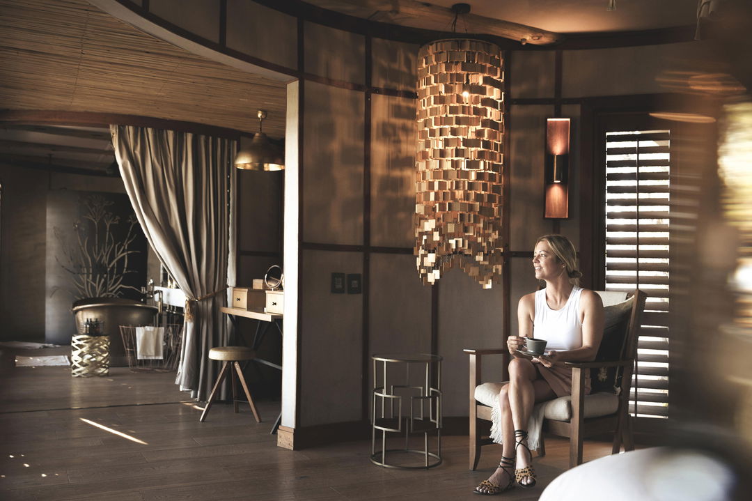 view of luxury suite interior and lady sitting on chair at Wilderness Mombo Camp