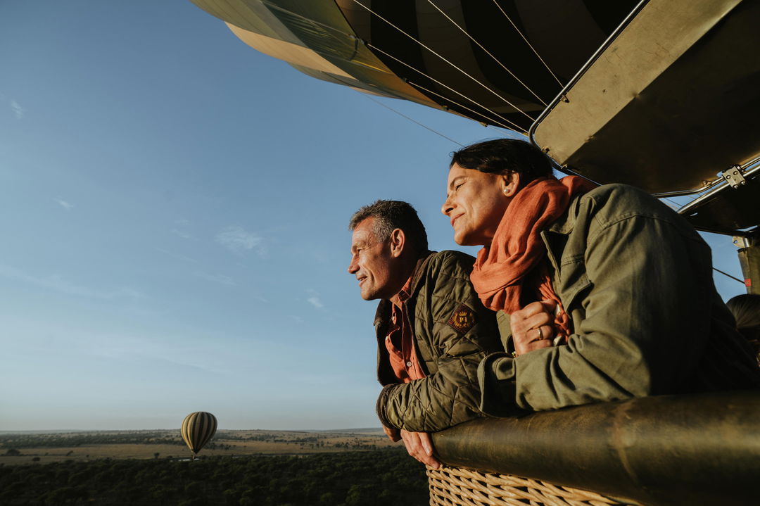 couple in basket of hot air balloon over plains of Wilderness Usawa tented camp Serengeti