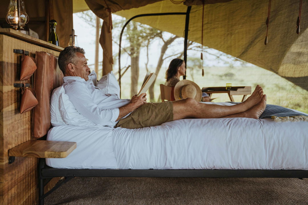 couple on bed in tented suite of Wilderness Usawa tented camp Serengeti